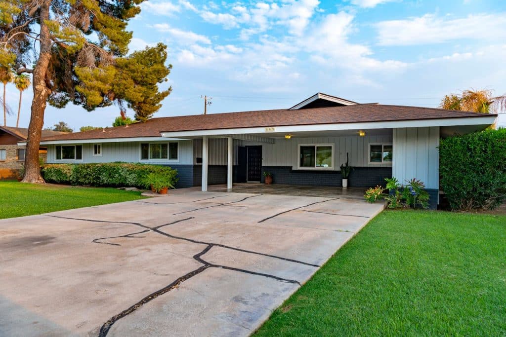 Suburban house with carport and lush lawn.