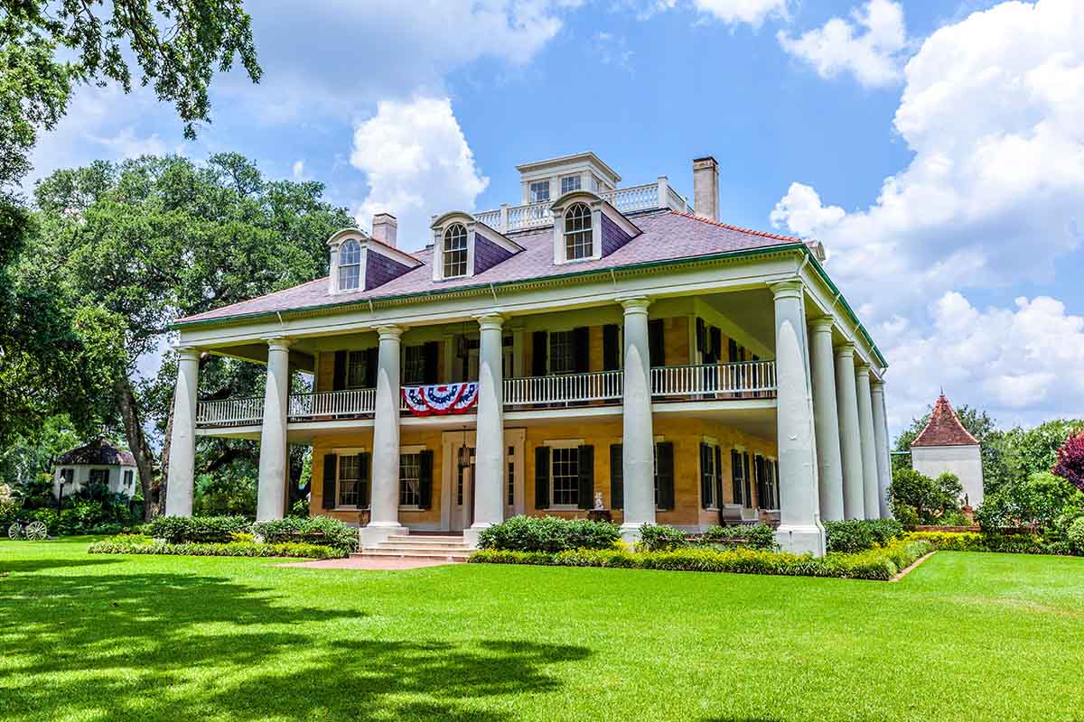 Historic Southern plantation house with columns and greenery.